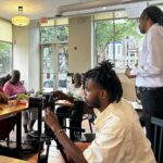 story circle participants sit around tables while one gentleman is standing and speakin