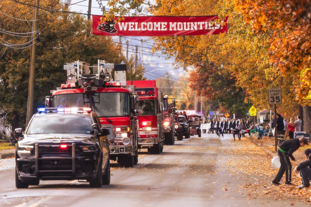fire trucks on parade down a tree-lined street in Mansfield with residents lining the sidewalks