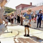 a young boy and girl use watering cans to sprinkle water on the sidewalk, making poetry appear like magic when the pavement gets wet