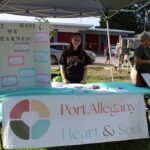 Allie O'Shea stands behind a table that the Port Allegany Heart & Soul team set up outside during a community event this summer to gather stories from residents about what they love about their community.