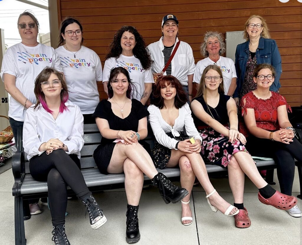 The following Rain Poetry participants are standing (back row) and seated (front row) Back from from left: Friends Memorial Library director Patty Kunicki, library support staff Brooke Lehman, library board of trustee Dani Newman, PA Wilds chief operating officer and PA Humanities board member Abbi Peters, library clerk and program director Anne Cleer, and Rain Poetry teaching artist and University of Pittsburgh at Bradford emeritus professor of writing Nancy McCabe. Front row from left: Rain Poetry poets Olivia Emer, Kya Haight, Aurora Forsythe, Allison Walters and Sophia Swanson at the Rain Poetry public reveal celebration in Kane.