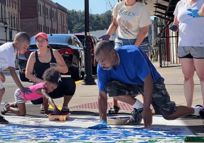 Residents dip their hands in paint to leave colorful handprints in community crosswalks.