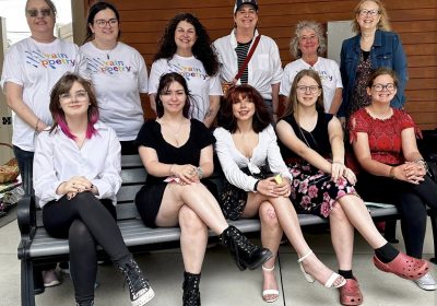 The following Rain Poetry participants are standing (back row) and seated (front row) Back from from left: Friends Memorial Library director Patty Kunicki, library support staff Brooke Lehman, library board of trustee Dani Newman, PA Wilds chief operating officer and PA Humanities board member Abbi Peters, library clerk and program director Anne Cleer, and Rain Poetry teaching artist and University of Pittsburgh at Bradford emeritus professor of writing Nancy McCabe. Front row from left: Rain Poetry poets Olivia Emer, Kya Haight, Aurora Forsythe, Allison Walters and Sophia Swanson at the Rain Poetry public reveal celebration in Kane.